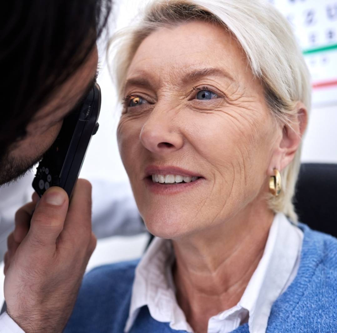 Optometry, eye check and woman with an optician for healthcare, consultation and vision exam. Lens test, health and senior patient with a male ophthalmologist with a light to look at visual problem